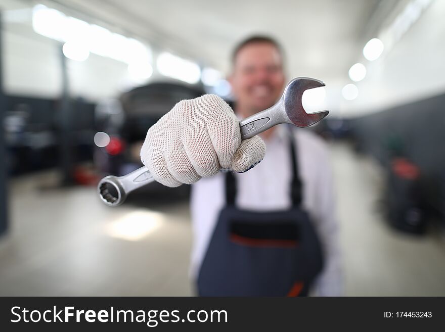 Close-up view of garage professional mechanic holding wrench. Macro shot of worker with special equipment to repair transport facility. Service station concept. Close-up view of garage professional mechanic holding wrench. Macro shot of worker with special equipment to repair transport facility. Service station concept