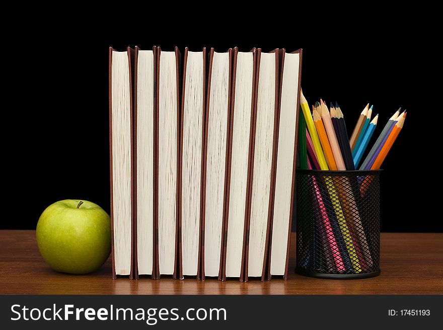 Stack Of Books And Apple On A Wooden Table
