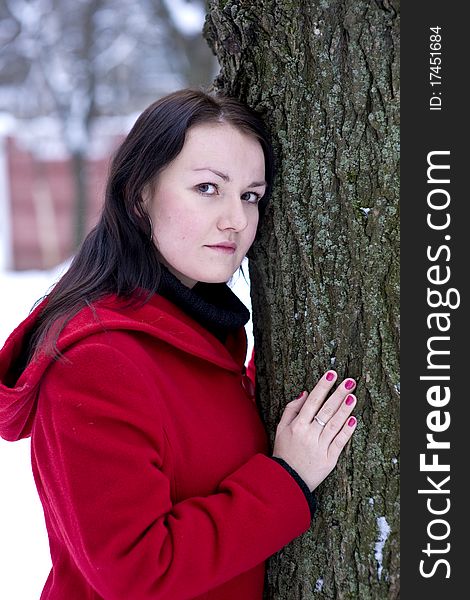Girl in the red coat leaning on tree. Girl in the red coat leaning on tree