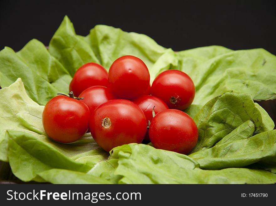 Cocktail tomatoes onto lettuce leaves onto black background