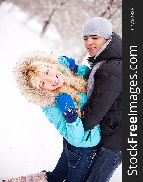 Happy young beautiful couple having a walk in winter park (focus on the woman). Happy young beautiful couple having a walk in winter park (focus on the woman)