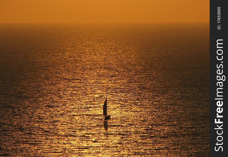 Sailboat glides lonely on the wide sea on golden water. Sailboat glides lonely on the wide sea on golden water