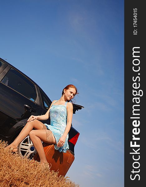 Girl with suitcase near the car