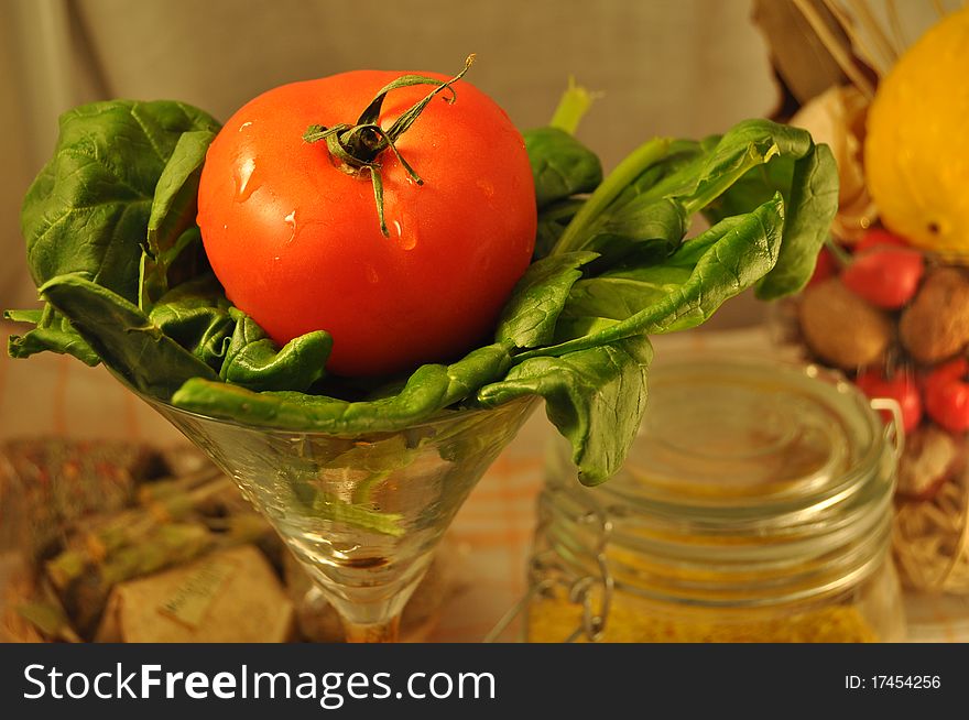 Green spinach and a red tomato in a glass. Green spinach and a red tomato in a glass