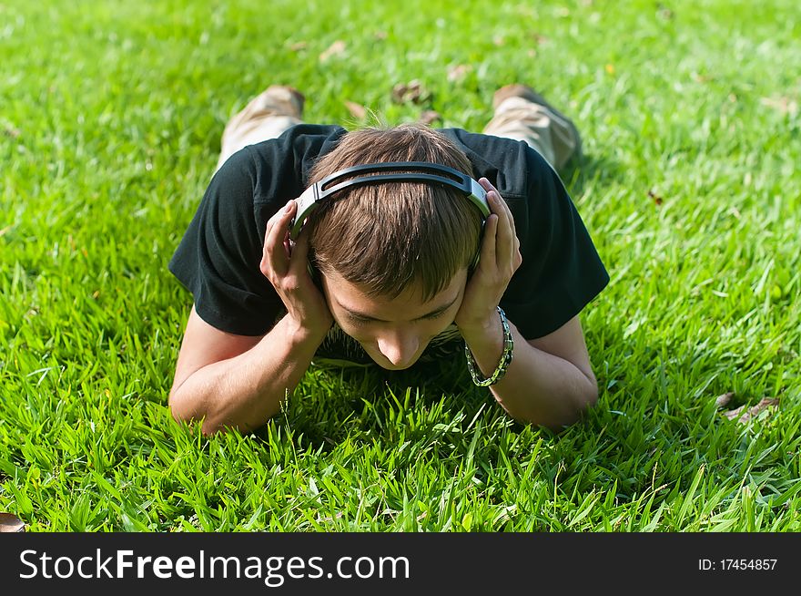 Young man is lying on the green grass and listening to music. Young man is lying on the green grass and listening to music