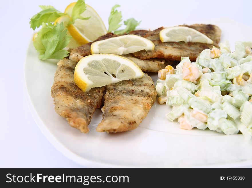 Fried fish with side salad (made of Pascal celery and corn) decorated with lemon