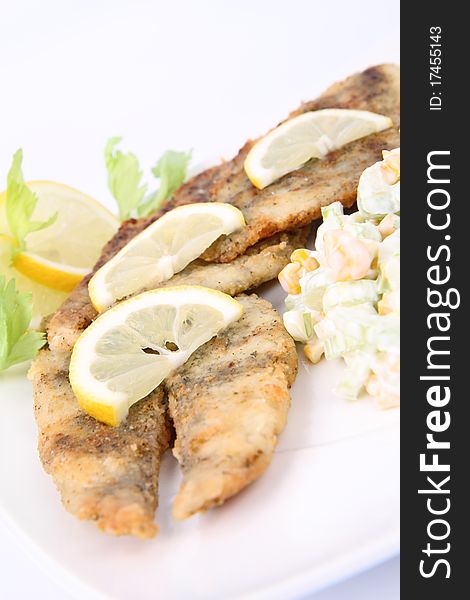 Fried fish with side salad (made of Pascal celery and corn) decorated with lemon