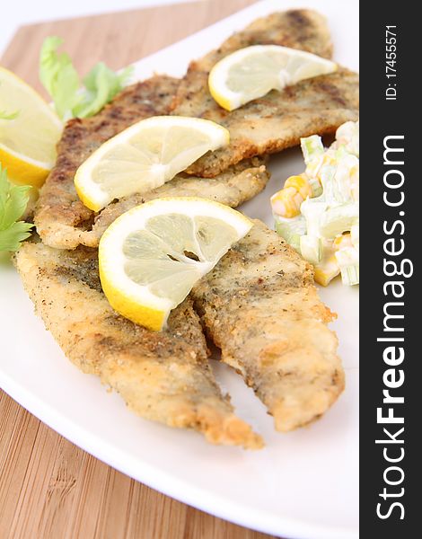 Fried fish with side salad (made of Pascal celery and corn) decorated with lemon