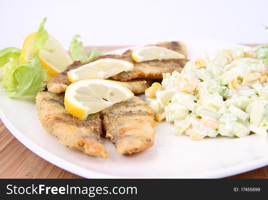 Fried fish with side salad (made of Pascal celery and corn) decorated with lemon