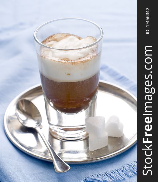 Cafe Latte in glass with spoon and sugar on plate. Cafe Latte in glass with spoon and sugar on plate