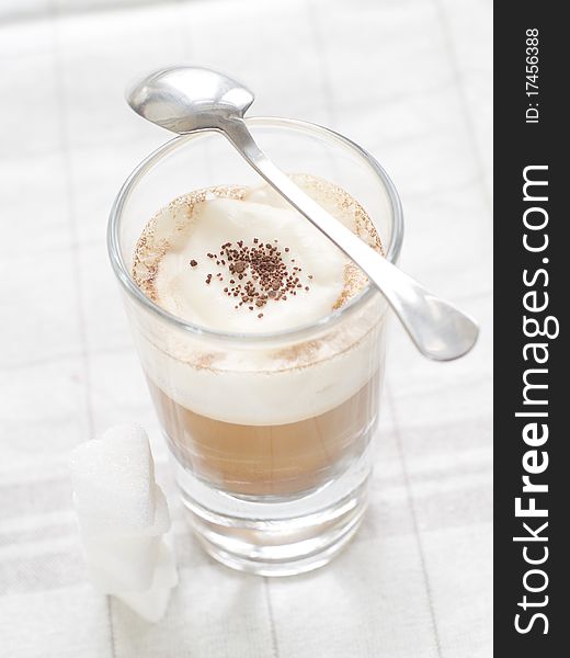 Cafe Latte in glass with spoon and sugar on plate. Cafe Latte in glass with spoon and sugar on plate