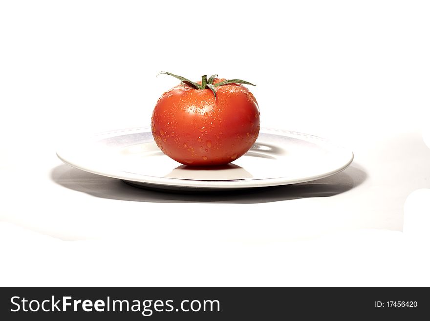 Close view detail of a red tomatoe on a plate isolated on a white background.