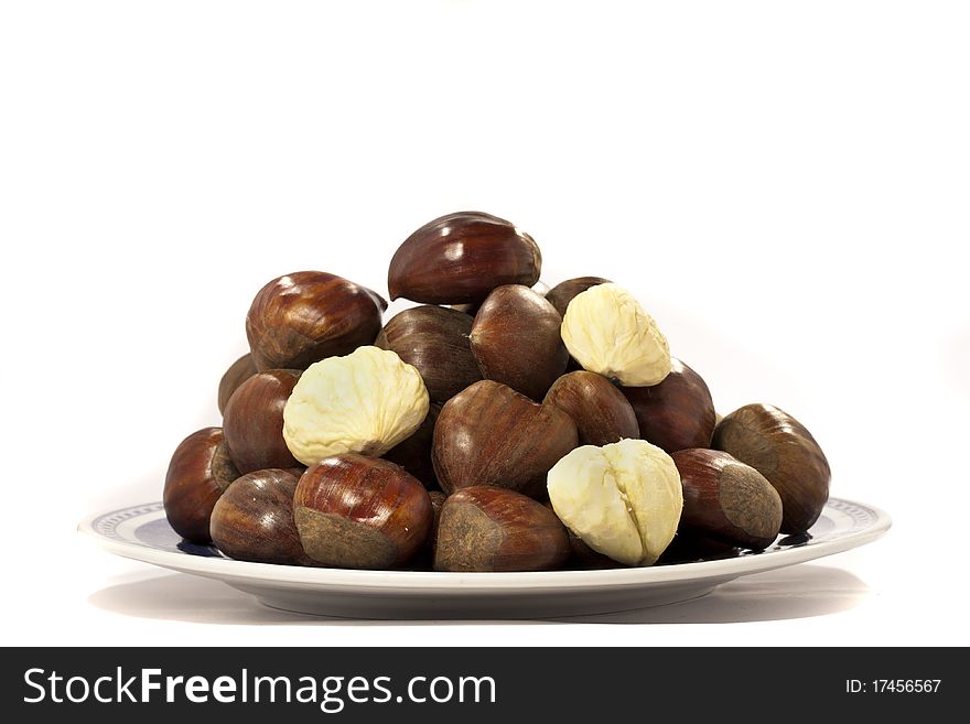 Close view detail of a pile of chestnuts on a plate isolated on a white background.