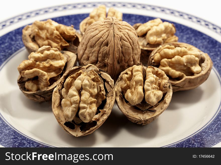 Close view detail of  some walnuts on a plate isolated on a white background.