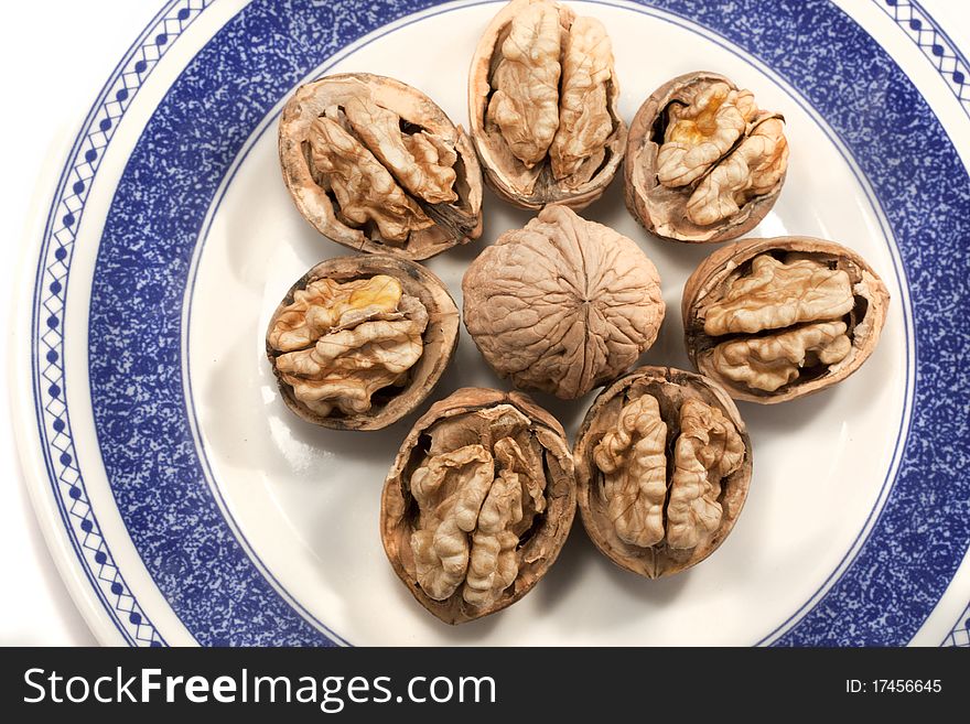 Close view detail of some walnuts on a plate isolated on a white background.