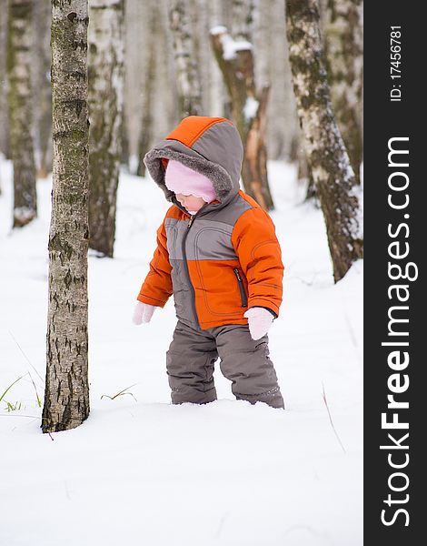 Cute baby walk in winter park among trees