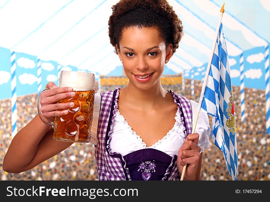 Beautiful brunette girl wearing a traditional bavarian dress holding a beer and a bavarian flag. Beautiful brunette girl wearing a traditional bavarian dress holding a beer and a bavarian flag