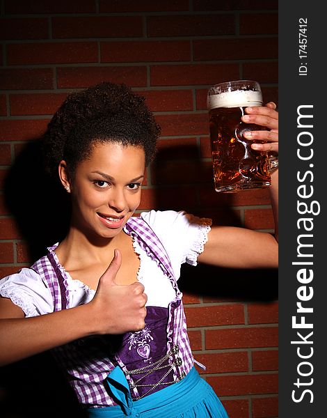 Beautiful brunette girl wearing a traditional bavarian dress holding a beer. Beautiful brunette girl wearing a traditional bavarian dress holding a beer