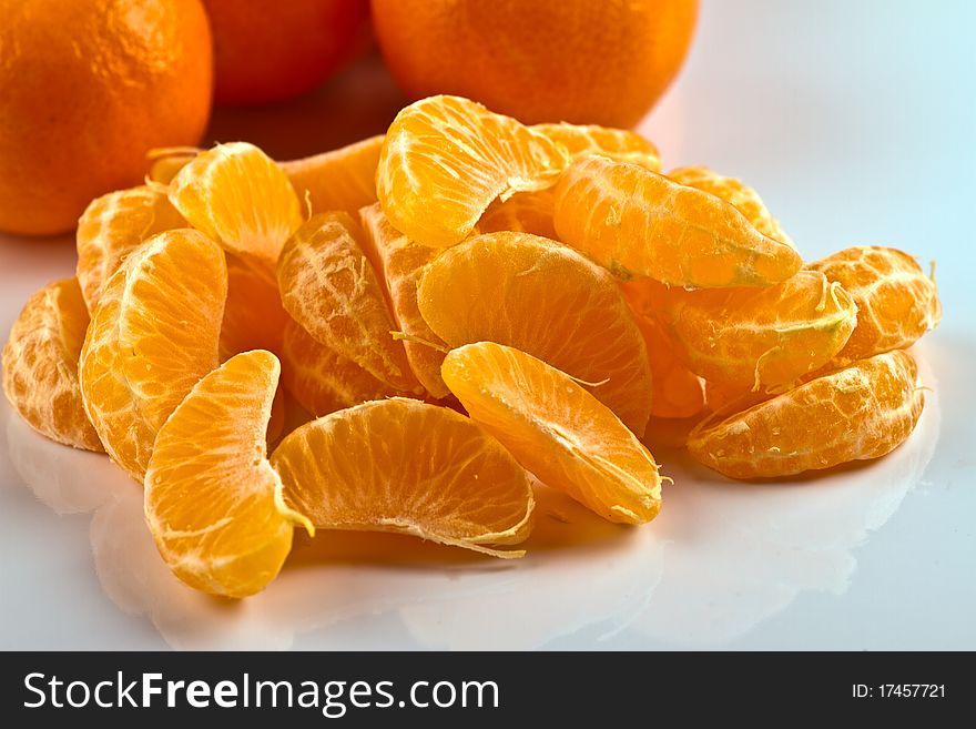 Peeled clementine and hole clementines on white surface. Peeled clementine and hole clementines on white surface