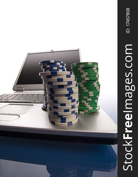Multi - colored gambling chips and laptop on blue background. Multi - colored gambling chips and laptop on blue background