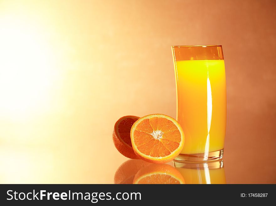 Sliced oranges near glass of orange juice on gradient background with reverberation