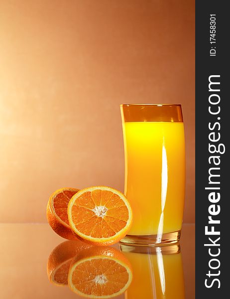 Sliced oranges near glass of orange juice on gradient background with reverberation