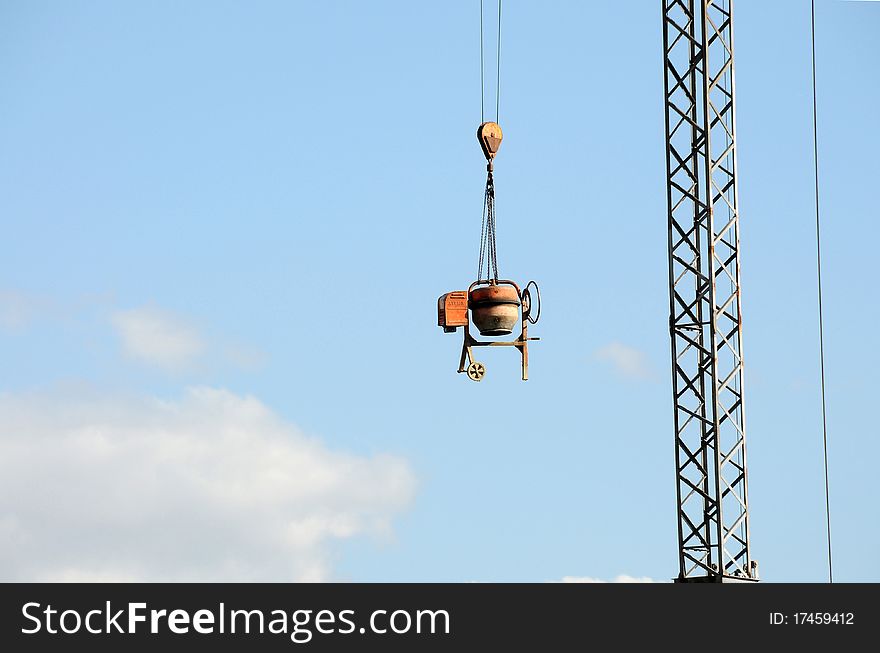 Cement mixer hanging from a crane at a construction site. Cement mixer hanging from a crane at a construction site
