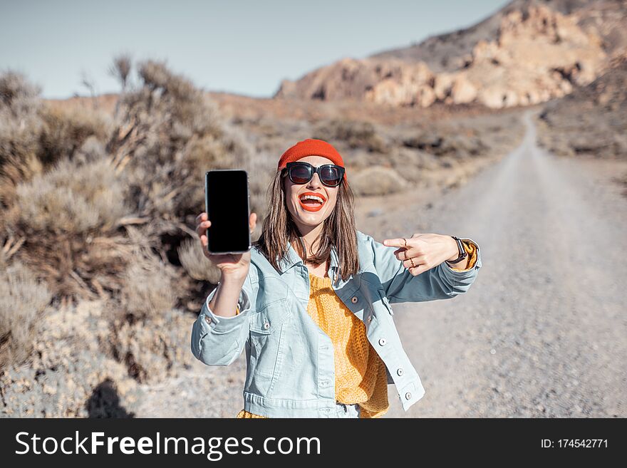 Woman With Smart Phone Traveling On The Desert Road