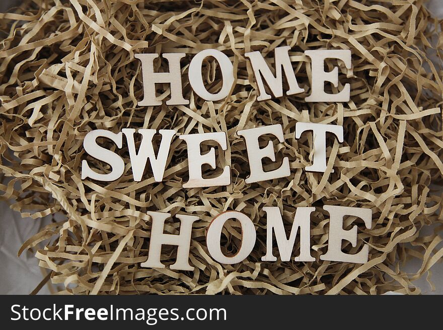 Letters Sitting On Brown Shredded Paper Forming The Words Home Sweet Home