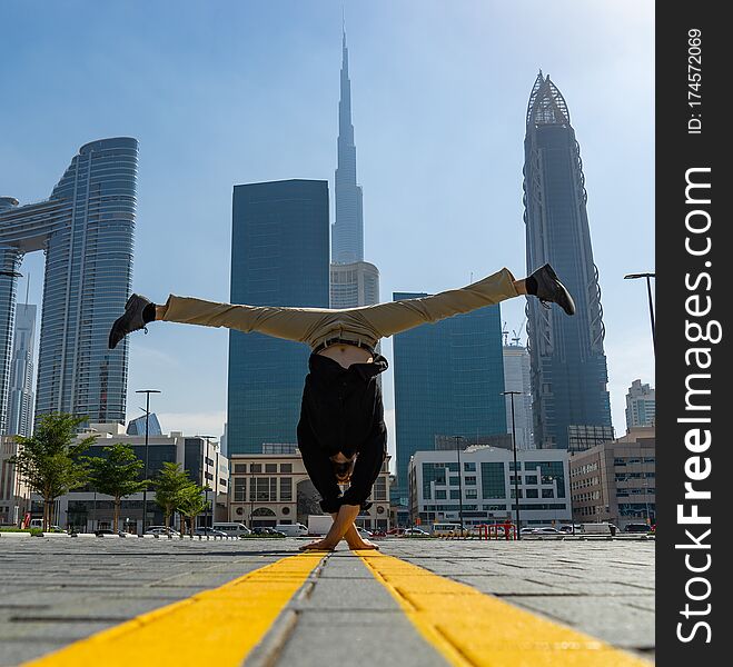 Acrobat keep balance one the hands with blurred Dubai cityscape. Concept of modern, business and unlimited possibility.