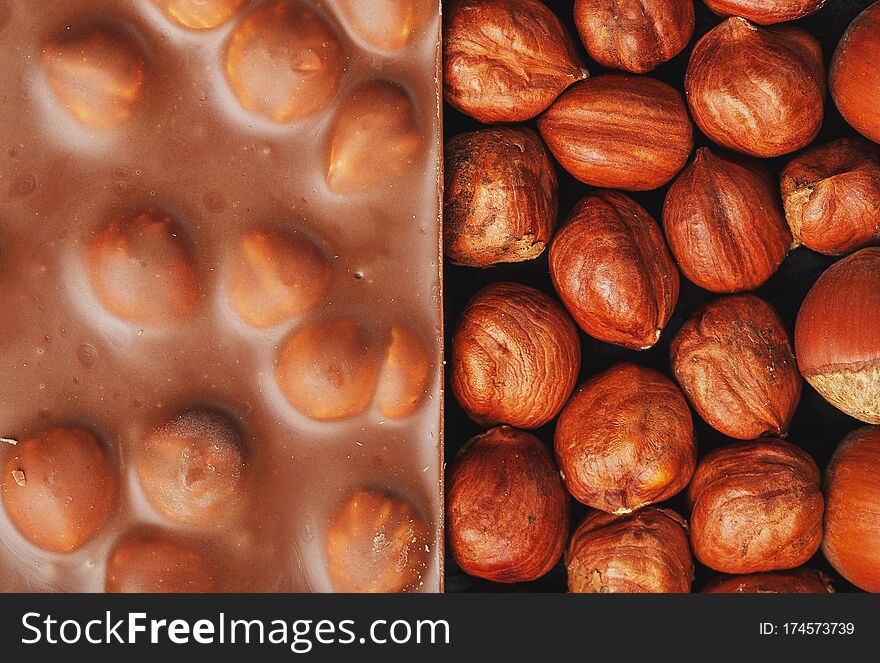 Chocolate with hazelnuts, nuts in a shell in the form of a solid texture. Dessert-milk chocolate with nuts. Confectionery. Full screen top view