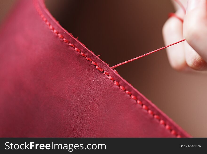 Conceptual profession of a Tanner. The woman`s hands closed around the needle and thread. The master sews the skin. Handmade work