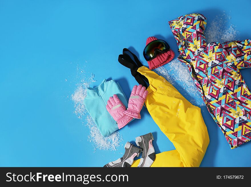 Stylish winter sport clothes on light blue background, flat lay