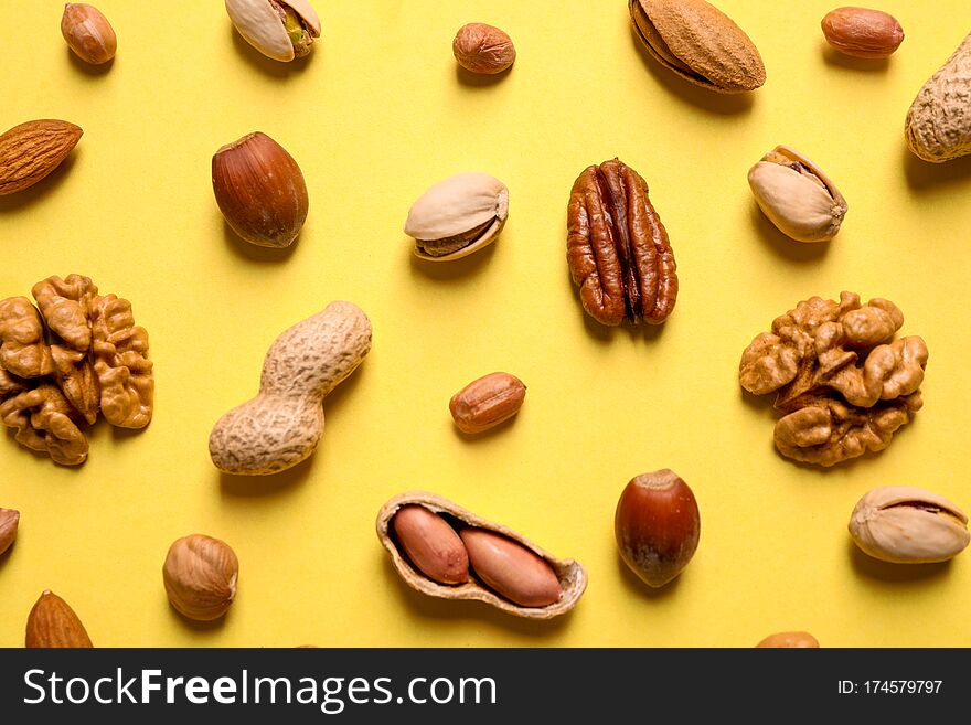 Different delicious nuts on yellow background, flat lay