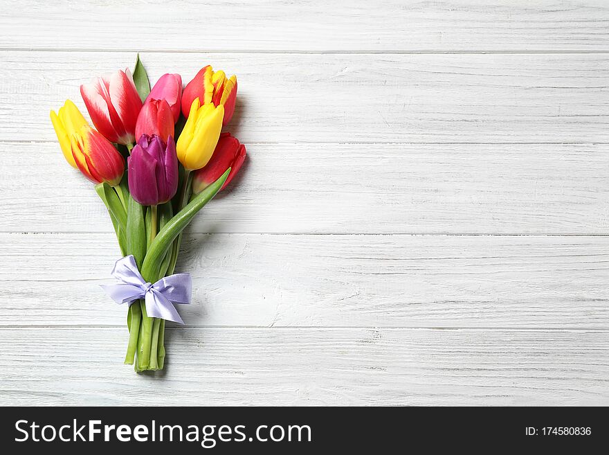 Beautiful spring tulips on white wooden table, top view. Space for text