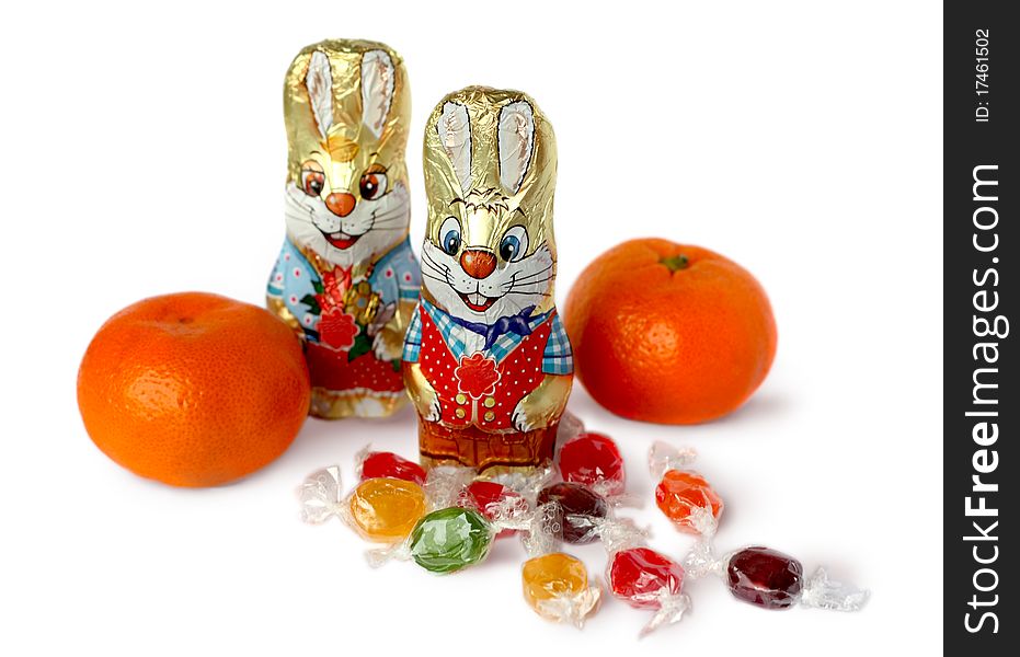 Chocolate bunnies, oranges and candy on a white background