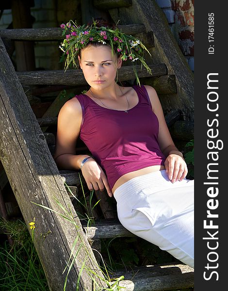 Portrait of the Beautiful young girl with a wreath from wild flowers on a head