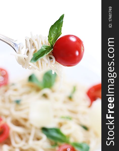 Spaghetti, basil and tomato on fork