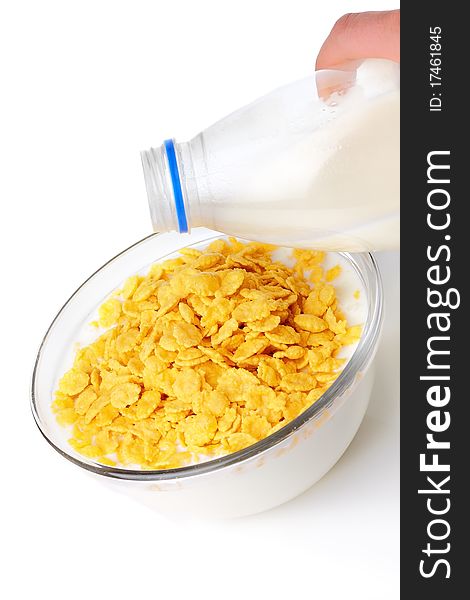 Granola with milk in glass bowl and spoon on white surface.