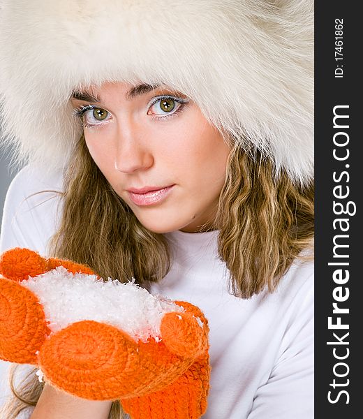 Beautiful winter girl in orange mittens with handful of snow