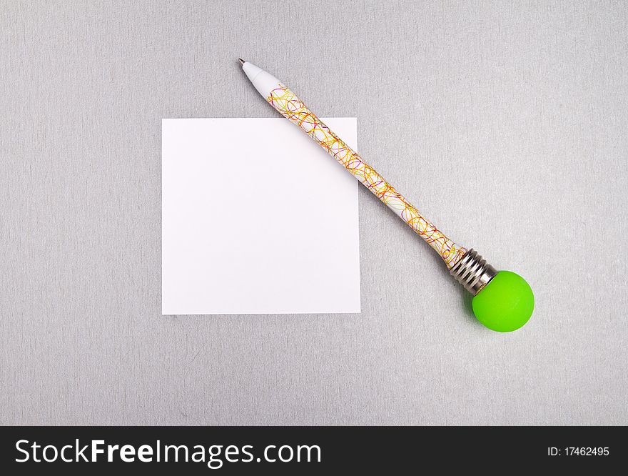 Funny colored pen with bright green light bulb and a blank paper. Funny colored pen with bright green light bulb and a blank paper