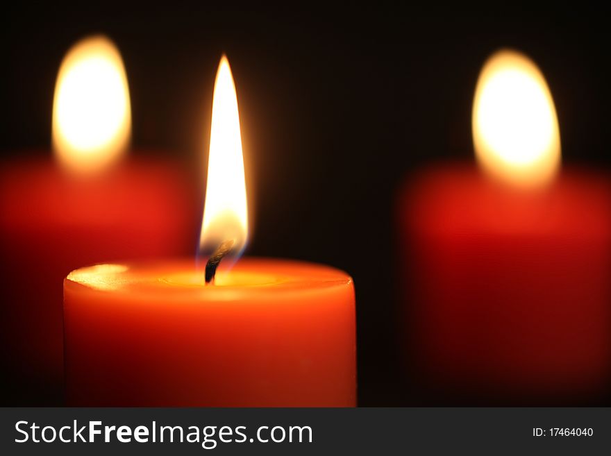 Close up of three Red candles lit against black