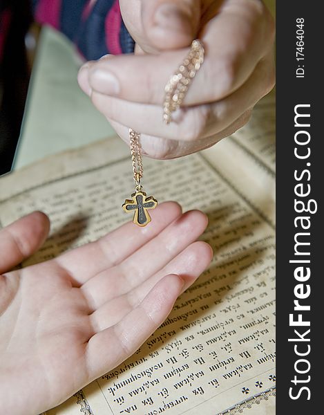 Hands close up with an orthodox cross against the orthodox bible. Hands close up with an orthodox cross against the orthodox bible