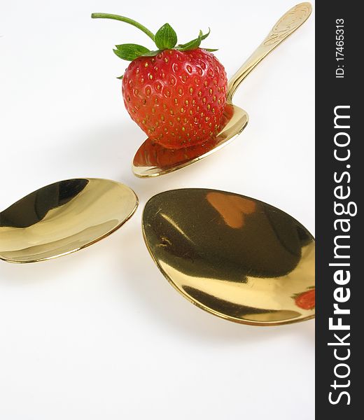 Abstract. Three gold spoon and single strawberry. Abstract. Three gold spoon and single strawberry