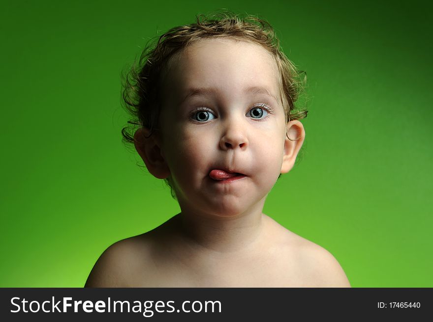 Close up portrait of cute little boy showing his tongue on green background