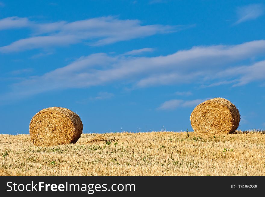 Hay bales in field against blue summer morning sky - landscape format. Hay bales in field against blue summer morning sky - landscape format