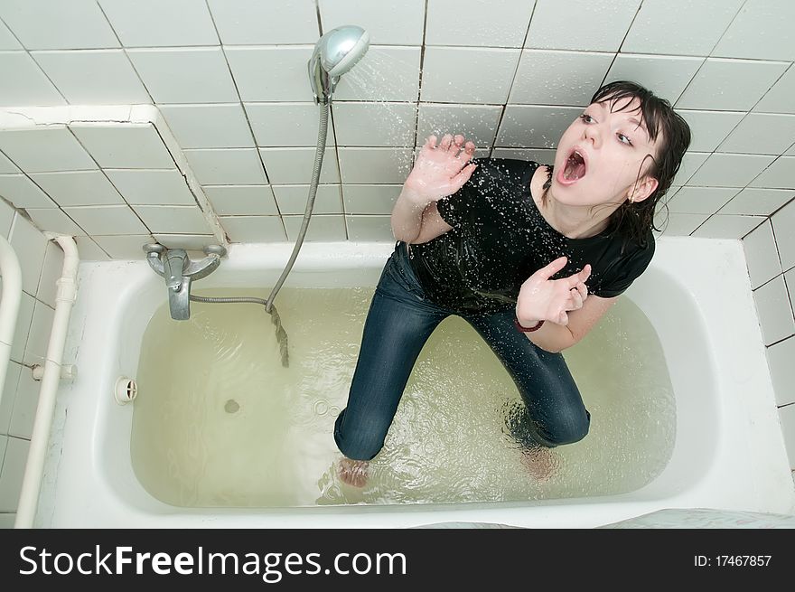 Girl in clothes in the bathroom under the shower. Girl in clothes in the bathroom under the shower