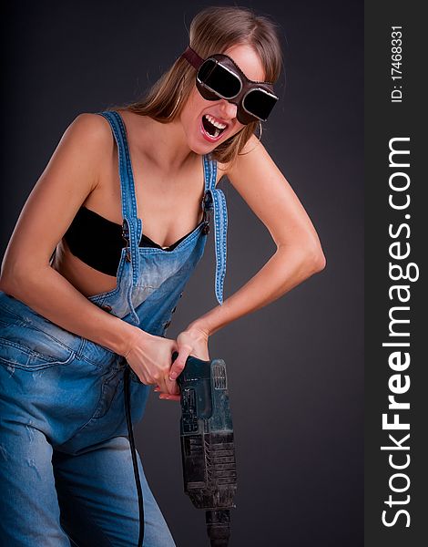 Girl with a drill in building overalls