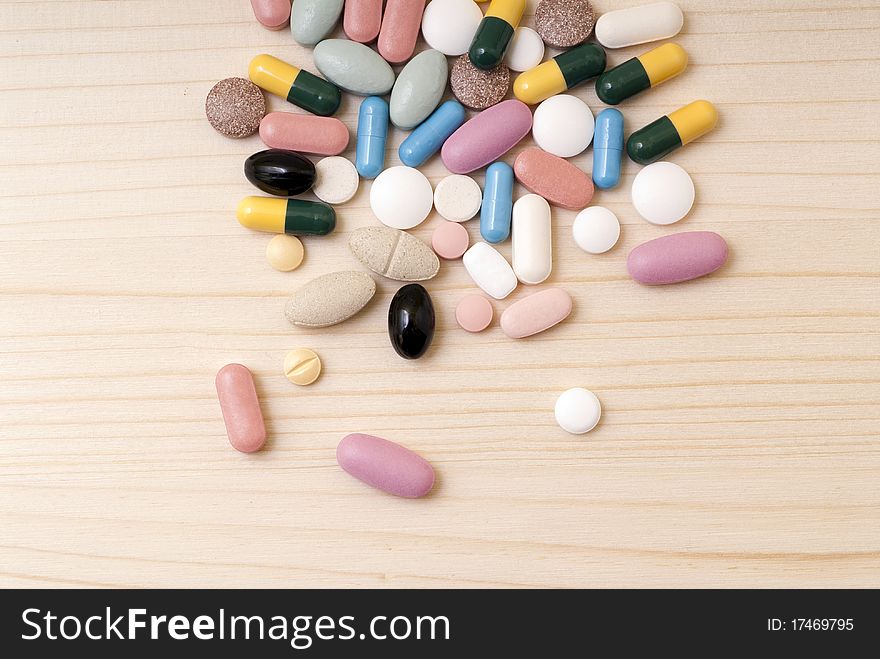 Pills scattered on a wooden board