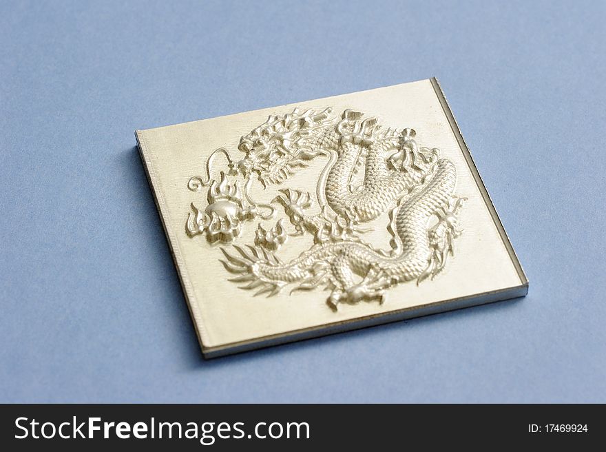 An engraving dragon plate isolated on blue.